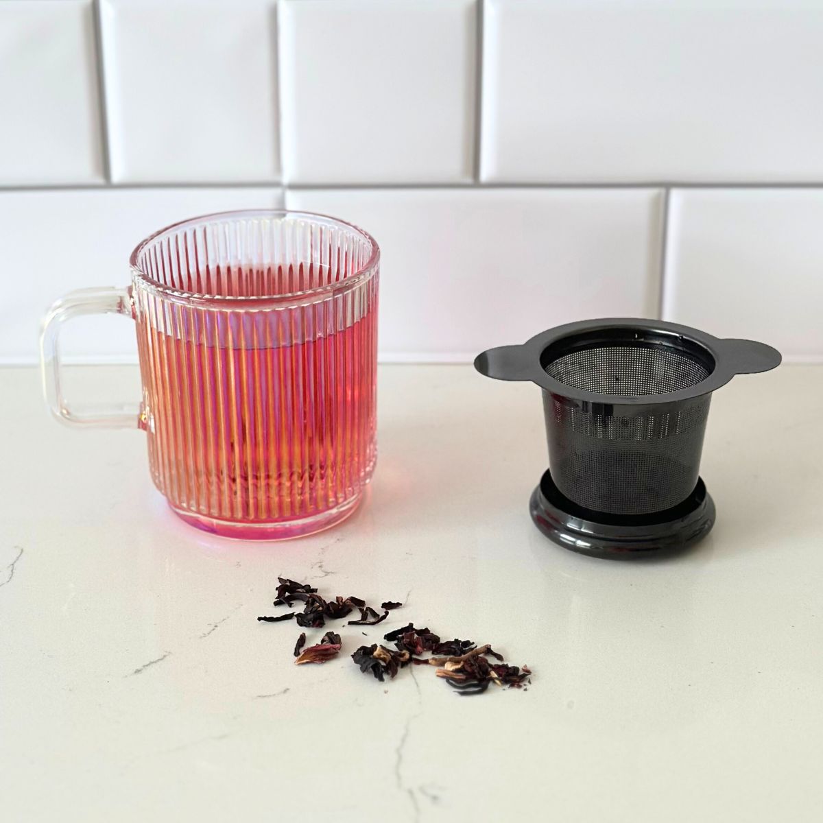 Black loose leaf tea infuser beside glass mug